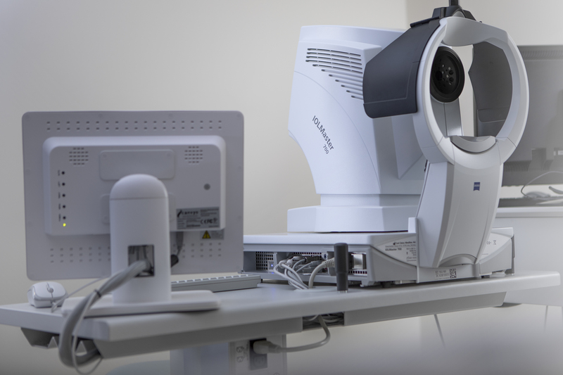 Nahaufnahme eines Augenuntersuchungsgeräts und eines Monitors in einer teamorientierten medizinischen oder optometrischen Praxis.