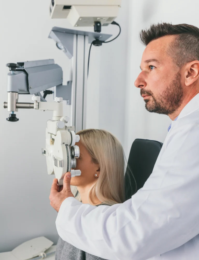 Optometrist mit Phoropter zur Untersuchung der Augen in einer modernen Klinik, die Angiographie am Auge anbietet.